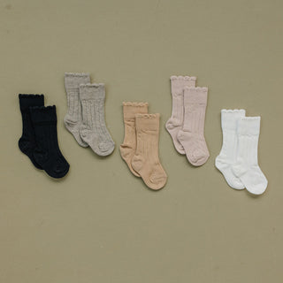 Set of five pairs of socks in black, gray, beige, pink, and white on a beige background

